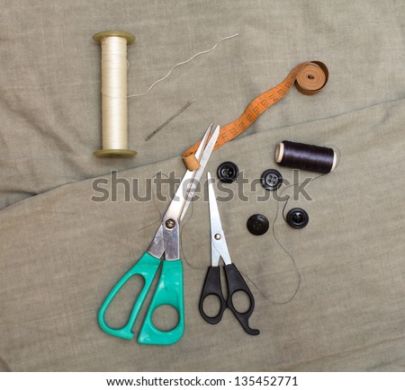 Tools for cutting and sewing lie on the fabric. Scissors, buttons and thread.