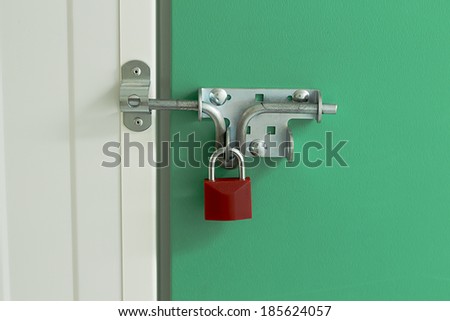 Close up image of a red padlock on a self storage unit with a green door