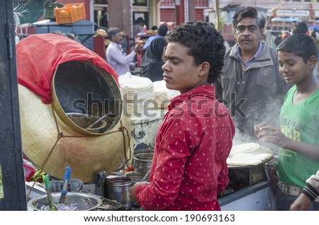 Jaipur, India - February 27, 2014 - Street food vendor preparing meal and snack for customers at local market during daytime