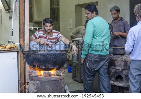 Jaipur, India - February 27, 2014 - Street food vendor preparing and selling meal and snack  for customers at local market during daytime