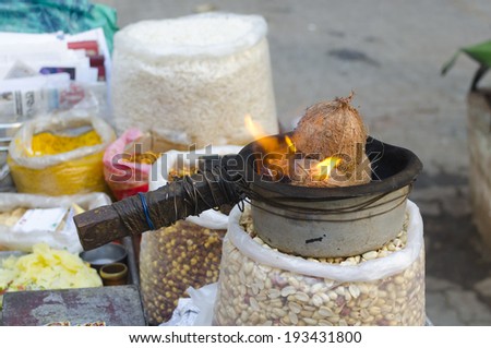 Street side snack stall of roasted nuts being warmed by small stove with coconut shells as source of fire in Mumbai India