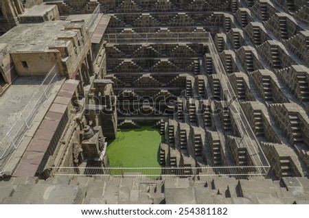 Stone step wells in Rajasthan India with zigzagging stairs down to the bottom to get water covered with green moss and lichen
