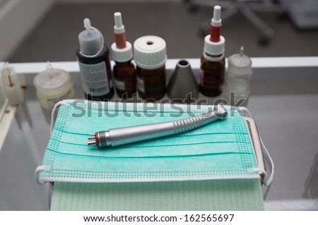 dental turbine hand piece is on the table surrounded by dental tool