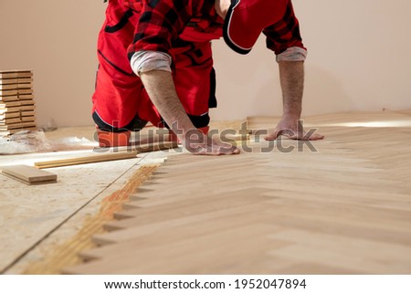 Handyman installing wooden flooring, Worker laying parquet flooring. Worker installing wooden laminate flooring.  Parquet and carpenter concept,