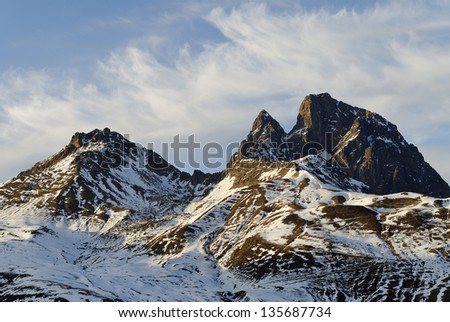 The peak of Noon of Ossau seen by oriental face, some snow remain, light of the end of day, semi-cloudy sky.