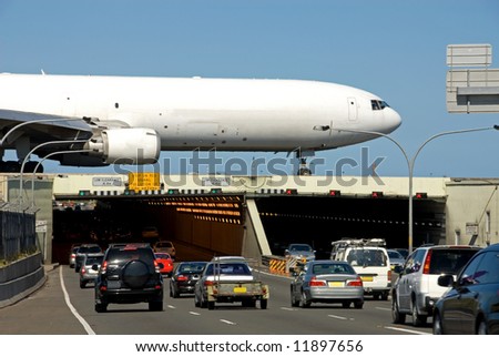 An aircraft, taxiing on the runway, which runs over the top of busy General Holmes Drive, Sydney, Australia