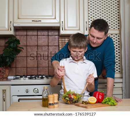 Portrait of a father and his son cooking in the kitchen. Healthy food - vegetable salad.