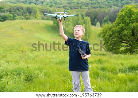 Happy boy with plane on a meadow in a sunny day. Smiling young boy preparing to launch RC plane.