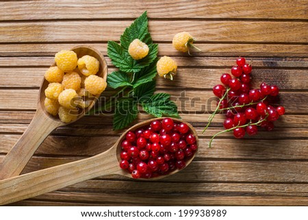 Berries on Wooden Background. Summer or Spring Organic Berry over Wood. Raspberries, Red currant . Agriculture, Gardening, Harvest Concept.Top view . Autumn berries and wooden spoons on an old board