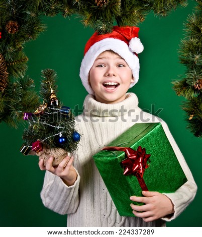 Surprised smiling boy in Santa hat with present. New Year. Christmas.