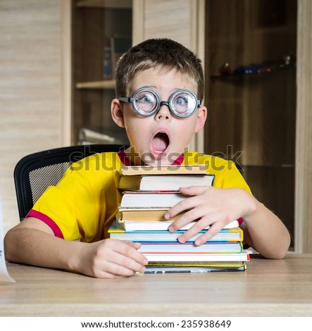Confused schoolboy in funny glasses screaming near the huge stack of books. Education.
