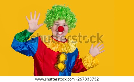 Portrait of a screaming clown with copyspace on yellow background. Funny kid in green wig in clown costume.