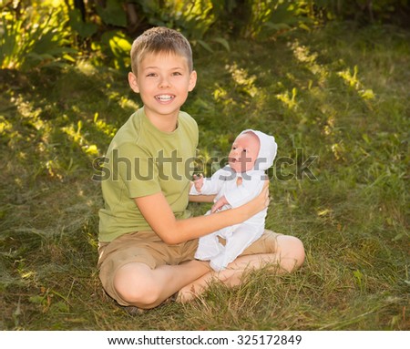 Portrait of happy brother and his newborn baby sister outdoor. Preteen boy with his little sister sitting on the grass summer day.