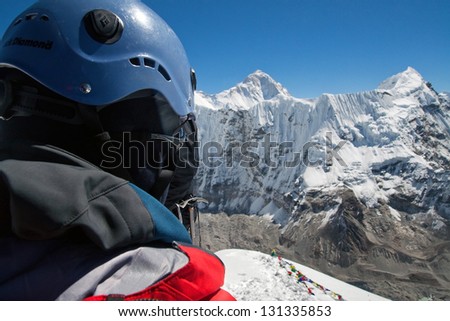 Mountaineer at summit looking out over mountain range