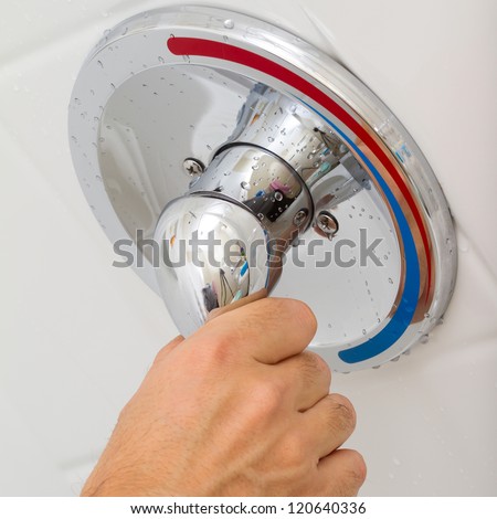 Human Hand switches a Shower faucet cold and hot water in the bathroom