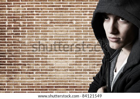 Young cool street style fashion male model posing at brick wall