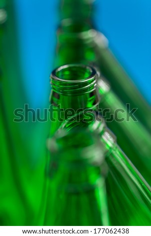 Composition of the four vertical green beer bottles and three diagonal green beer bottles on a blue background