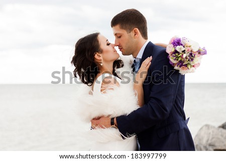 Happy newlyweds on the beach. Portrait of loving bride and groom near the sea.