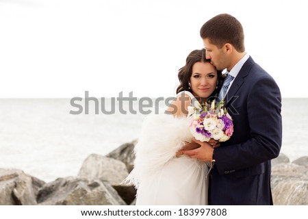 Happy newlyweds on the beach. Portrait of loving bride and groom near the sea.