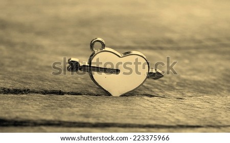 Sepia valentine\'s day background. Heart with cupid arrow on wood