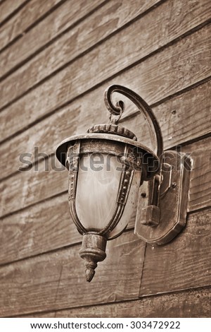 Old style photo of Antique lamp hanging on old wood wall.