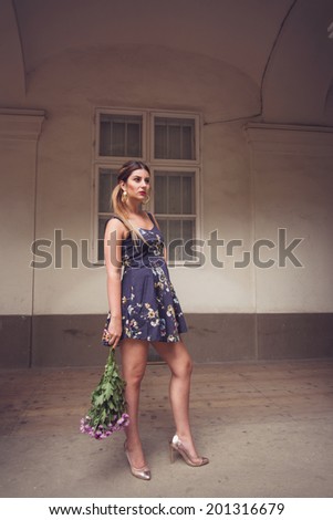 Fashionable woman wearing a blue floral print dress, gold shoes