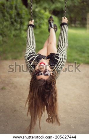 Fashion shoot of sexy woman swinging upside down wearing a black romper jumpsuit