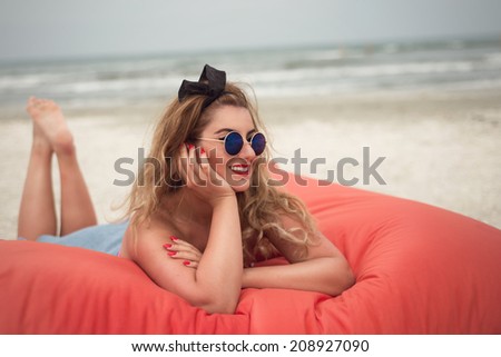 Beautiful woman sunbathing relaxing on a beach lounge large pillow looking to the right