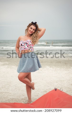 Beautiful woman relaxing on a beach lounge large pillow wearing a sexy pink top and denim skirt
