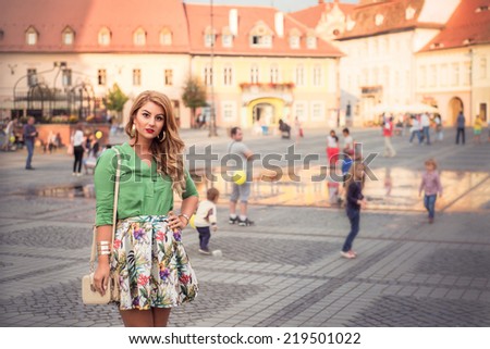 Fashion elegant stylish woman posing on streets of European city in summer evening weather. Sensual blonde vogue girl street style shooting. Landscape portrait with copy space on the right.