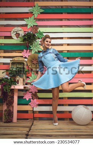 Beauty playful girl wearing baby blue dress. Colorful decor Studio Shot of Fashion Woman. Vivid Colors. Rainbow Colors painted on wood. Vintage objects