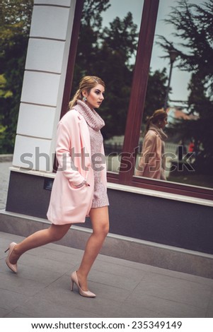 Fashion shot of a woman in pink coat and knitted dress. Urban photo shooting of sexy and beautiful  woman in winter holiday outfit. Stylish Look