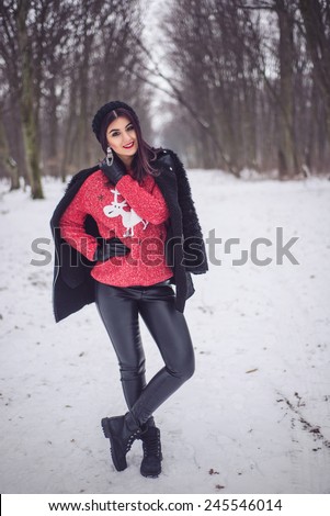 Cute girl wearing fashion deer sweater and sexy leather pants in winter snow scenery