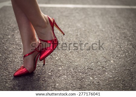 Woman wearing red high heel shoes. Exact focus on concrete. Copy space