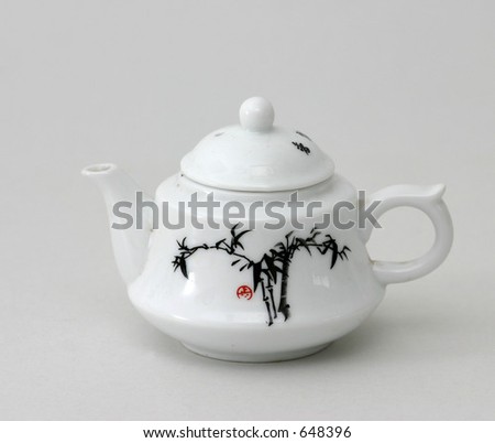 Small China teapot with Chinese bamboo painting on side with white background.
