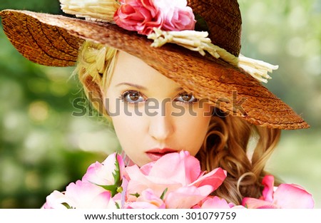 Beautiful girl with flowers in the garden with straw hat. Natural beauty.