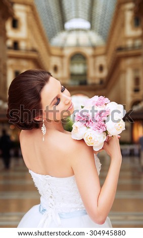 Bride standing in front of beautiful gallery. Bridal make up and hairstyle. Elegance in Milan, Italy.