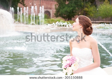 Beautiful bride sitting in front of fountain. Beautiful location wedding. Pretty bouquet.