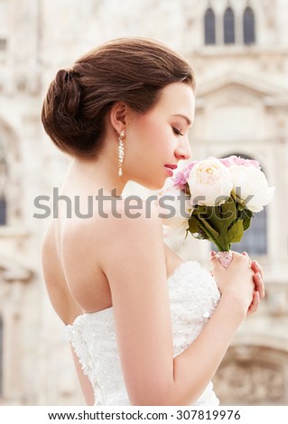 Bride standing in front of beautiful church. Wedding make up and hairstyle. Elegance.