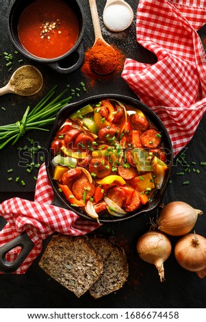 Traditional Hungarian stew with peppers and sausage called lecso in a cast iron skillet on a black background, top view Stock fotó © 