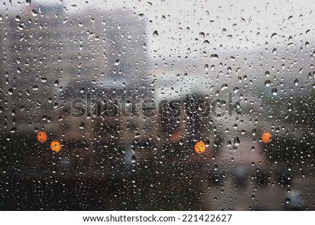 Rain drops on the window in the big city. Big building on the background.