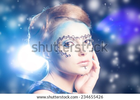 Winter Beauty Woman. Christmas Girl Makeup and Blue Dress. Holiday Make-up. Snow Queen over Gray Snow Background Close-up Portrait.