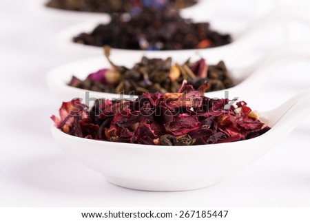 Dry tea in white bowls on white background. Leaves of red, green and black tea. Macro photo.