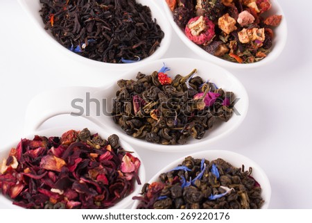 Dry tea in white bowls on white background. Leaves of red, green and black tea. Macro photo.