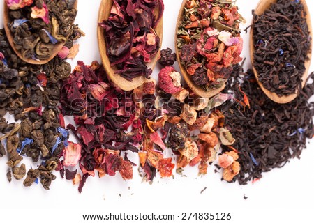 Dry tea in wooden plates and spoons, on white background. Leaves of red, green and black tea. Macro photo.