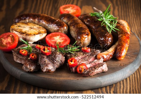 Close-up photo of mixed grilled meat platter. Beef, pork, poultry, sausages, grilled garlic, chili pepper, red tomatoes on wooden rustic background. ストックフォト © 