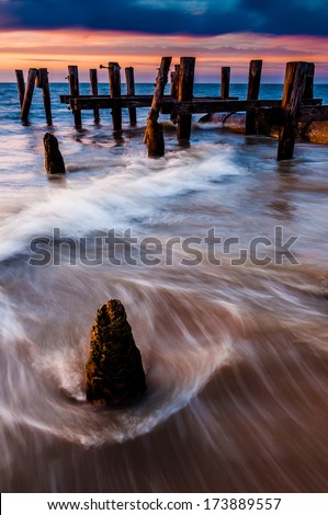Waves swirl around pier pilings in the Delaware Bay at sunset, seen from Sunset Beach, Cape May, New Jersey.