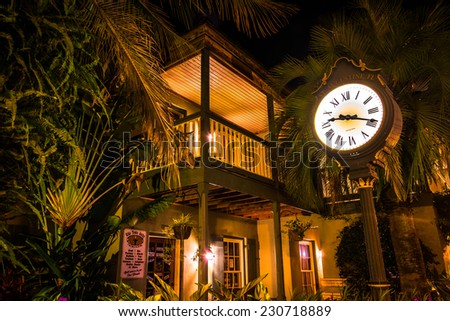 Shop and clock surrounded by palm trees and foliage at night, in St. Augustine, Florida.