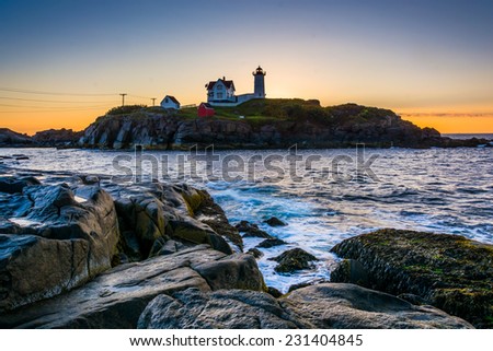 Waves splashing on rocks and Nubble Lighthouse at sunrise, at Cape Neddick, in York, Maine.