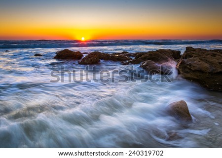 Rocks and waves in the Atlantic Ocean at sunrise in Palm Coast, Florida.